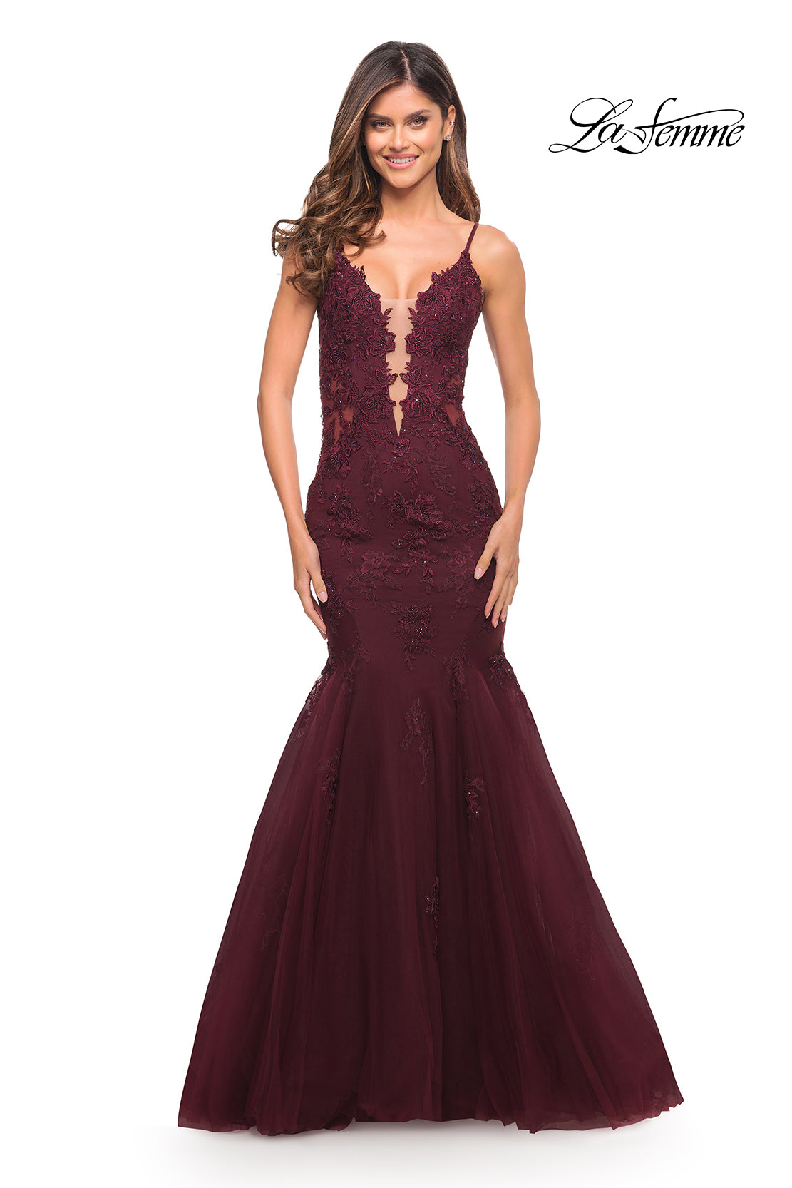 A woman wears the La Femme Embroidered-Lace Long Mermaid Prom Dress in burgundy, featuring a sheer lace bodice and deep V neckline. The La Femme logo appears in the top right corner.
